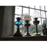 Two Victorian brass columnar oil lamps and another oil lamp with blue glass reservoir and fluted