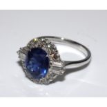 18ct white gold ring set with an oval blue sapphire, tapered baguette cut diamonds and round