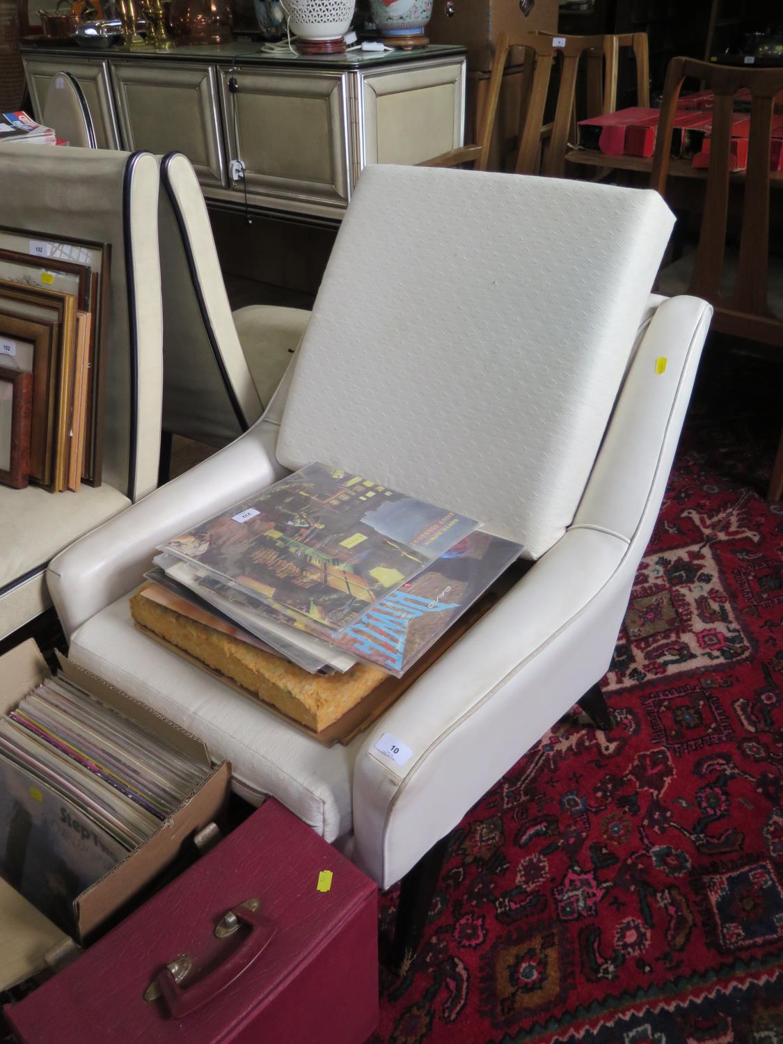 A 1950s cream faux leather armchair, the reclined button back on ebonised square moulded legs