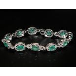 18ct white gold emerald and diamond line bracelet. Oval emeralds 7.12ct total. Diamonds 1.59ct total