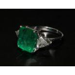 18ct white gold ring set with a large emerald-cut emerald flanked by trilliant cut diamonds.