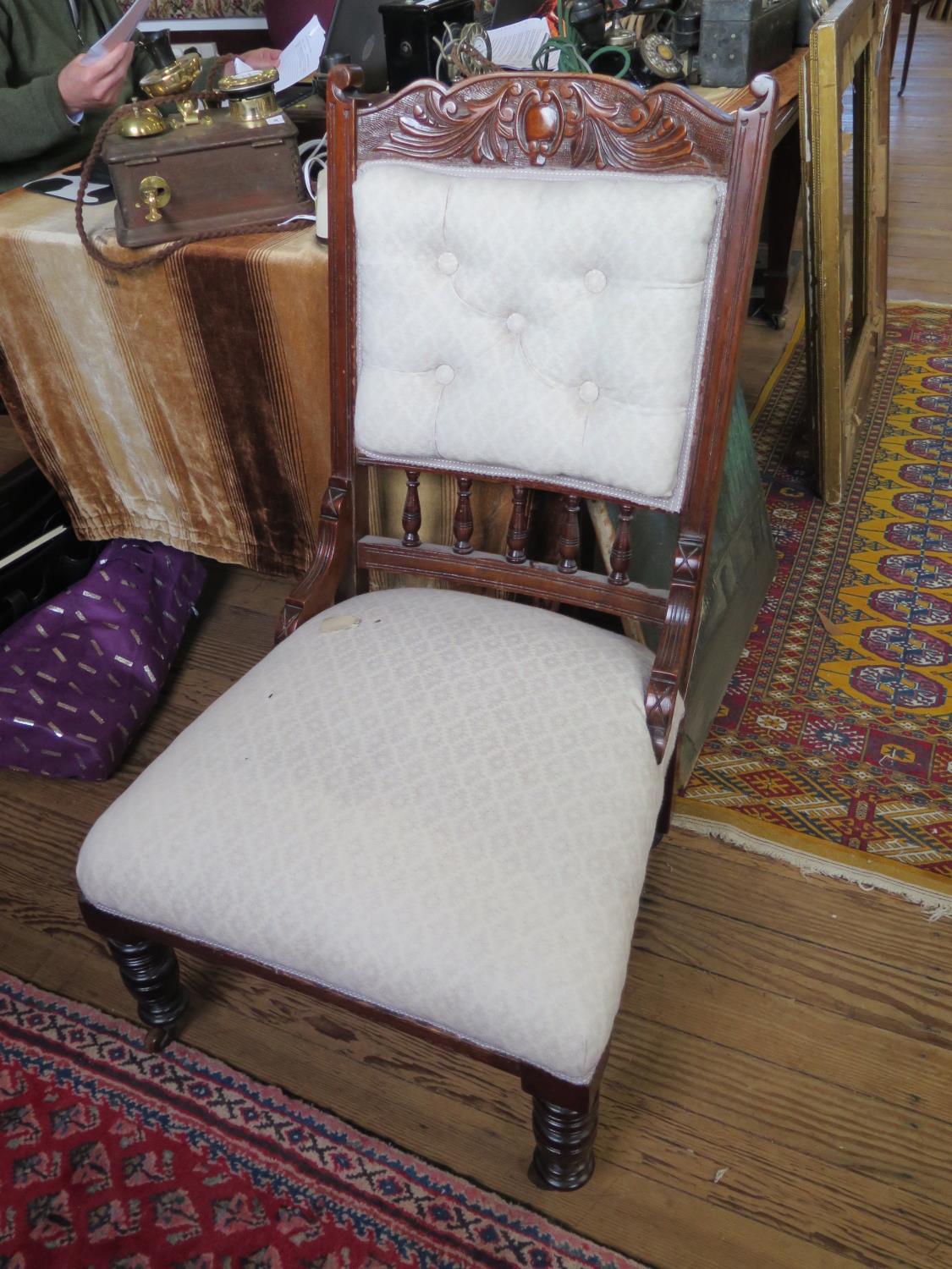 An Edwardian walnut lady's fire side chair, with carved top rail, button back and ring turned