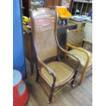 A Victorian elm and cane high back armchair, with ring turned legs joined by stretchers, on later