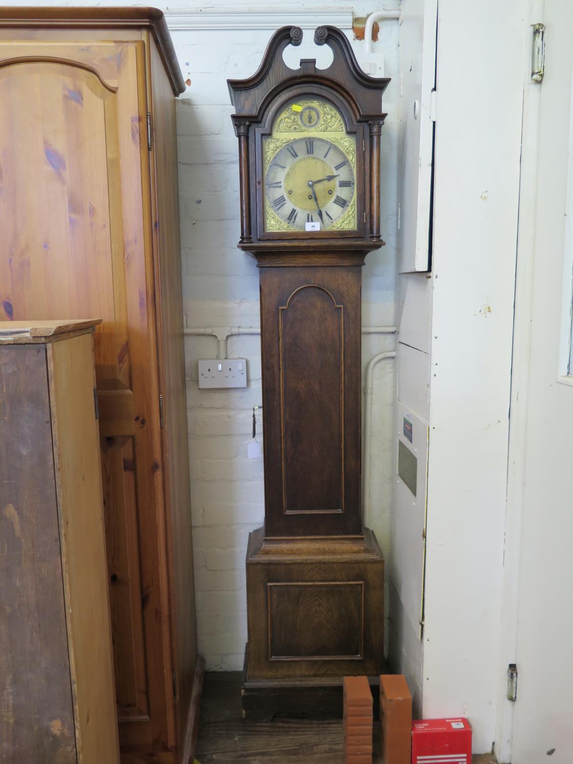 An early 20th century oak longcase clock, the swan neck pediment over a brass 10" dial with matted