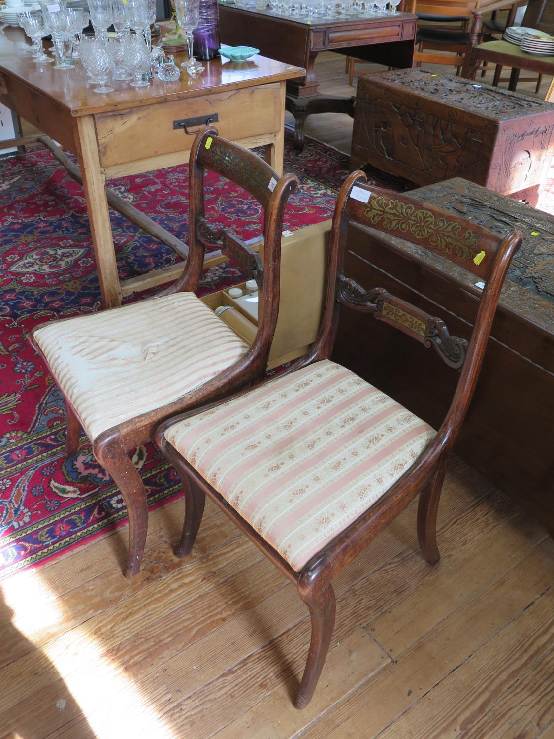 A pair of Regency brass inlaid rosewood dining chairs, the scroll carved backs over later drop-in