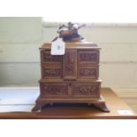A Black Forest carved walnut jewellery box, the hinged top surmounted by two birds, over four hinged