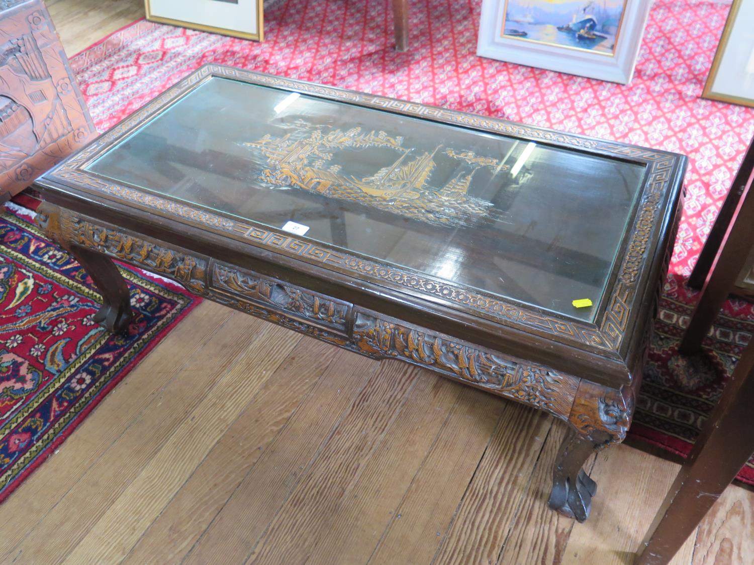 An Anglo-Chinese carved wood coffee table, the top carved with sailing vessels on a coastline, on