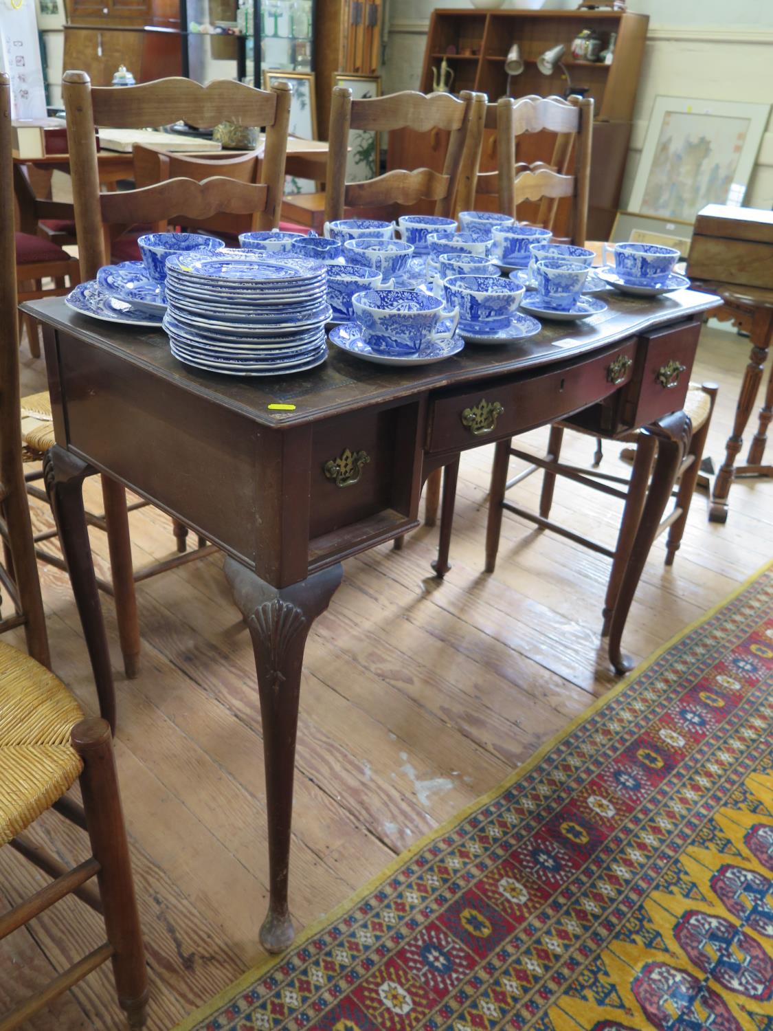 A 1920s mahogany lady's writing table, the leather top over a bowed drawer and two other frieze