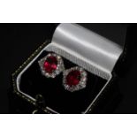 A Pair of 18ct white gold oval treated ruby and diamond cluster studs. Rubies 5.54ct. Diamonds 1.