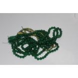 Earth mined round polished treated green beads on an adjustable tassle string. 764.00ct