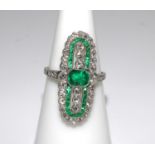 A platinum elongated oval shaped ring set with emeralds and diamonds. Emeralds 0.78ct approx. Size L