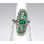 A platinum elongated oval shaped ring set with emeralds and diamonds. Emeralds 0.78ct approx.
