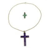 A gold colour metal cross set with possible emerald and amethyst suspended on a 14 carat chain