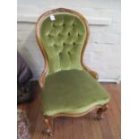 A carved beech nursing chair with castors and light green velvet upholstery