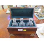 A Rosewood Tantalus. Of casket form. Fitted with three decanters with stoppers. Complete with key.