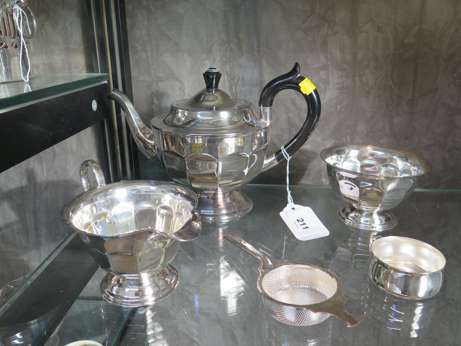 A three-piece silver plated tea set and strainer (4)