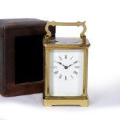 AN EARLY 20TH CENTURY BRASS CARRIAGE CLOCK OR TIMEPIECE the enamel dial with roman numerals, the