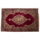 AN ORIENTAL RED GROUND RUG with decorative flower ornament to the central cartouche and banded