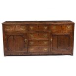 A 19TH CENTURY OAK DRESSER with six various drawers around twin panelled cupboard doors and standing