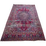 AN EARLY TO MID 20TH CENTURY MIDDLE EASTERN RED GROUND CARPET with a central stylised flower motif