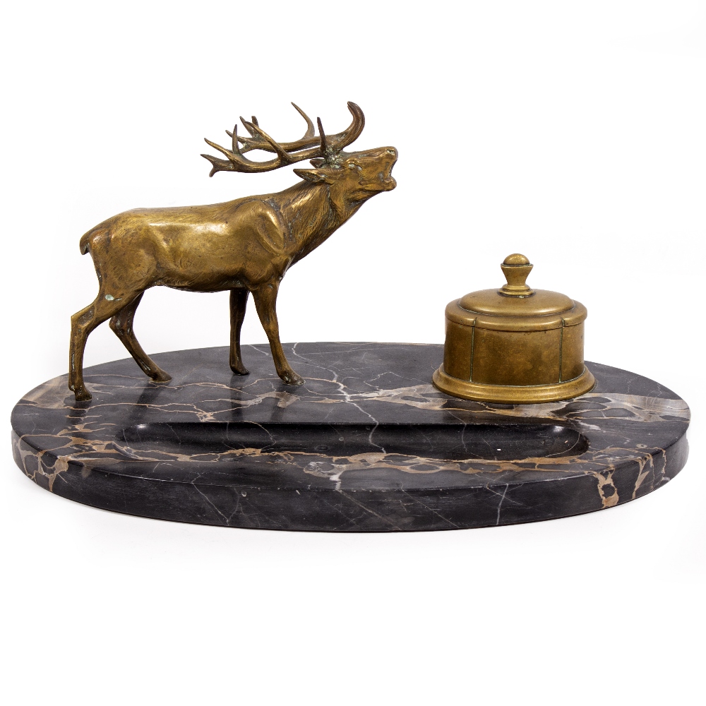 A LATE 19TH / EARLY 20TH CENTURY BRASS STAG AND INKWELL DESK STAND with an oval black marble base,