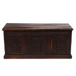 A 17TH CENTURY STYLE PANELLED OAK CHEST with carved decoration to the front, 130cm wide x 54cm