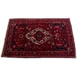 A MODERN ORIENTAL RED GROUND RUG with floral decoration to the central field and within a triple