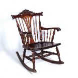 A VICTORIAN STYLE MAHOGANY ROCKING CHAIR with a carved crest and spindle supports, 64cm wide x