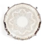 A VICTORIAN SILVER SALVER with chased and engraved decoration and four claw and ball feet, 30cm