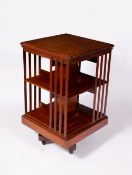 AN EDWARDIAN WALNUT ROTATING BOOKCASE with cast iron brackets to the stand and on ceramic casters,