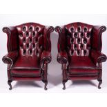 A PAIR OF RED LEATHER UPHOLSTERED WING BACK ARMCHAIRS each 84cm wide x 71cm deep x 102cm high