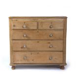 A VICTORIAN PINE CHEST OF TWO SHORT AND THREE LONG DRAWERS with porcelain set turned knob handles,