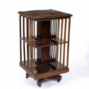 AN EDWARDIAN MAHOGANY ROTATING BOOKCASE on a wooden stand with decorative satinwood crossbanding