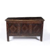AN ANTIQUE OAK COFFER with plank top and chip carved decoration to the triple panel front,