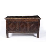 AN ANTIQUE OAK COFFER with plank top and chip carved decoration to the triple panel front,