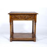 AN OAK TWO TIER OCCASIONAL TABLE with single frieze drawer by Brights of Nettlebed with carved