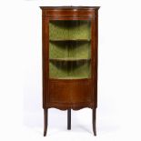 AN EDWARDIAN MAHOGANY SERPENTINE FRONTED CORNER FLOOR STANDING DISPLAY CABINET with green silk lined