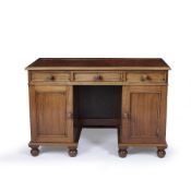 A HARDWOOD LEATHER INSET KNEEHOLE DESK with three drawers and two cupboard doors all standing on