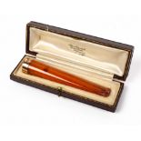 AN ALFRED DUNHILL AMBER CIGAR HOLDER with 9 carat gold ring mount and set within a fitted case,