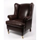 A LATE 20TH / EARLY 21ST CENTURY LEATHER UPHOLSTERED WING BACK ARMCHAIR with turned front legs and