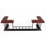 A CONTEMPORARY RED LEATHER BUTTON UPHOLSTERED CLUB FENDER on a black painted wrought iron base,