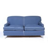 A BLUE UPHOLSTERED HOWARD STYLE SOFA with white piping and standing on white painted square tapering