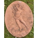 AN OVAL TERRACOTTA TYPE MOULDED WALL PLAQUE depicting a cherub with grapes, 37cm x 28cm Condition: