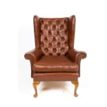 AN EARLY TO MID 20TH CENTURY BROWN LEATHER BUTTON UPHOLSTERED WING BACK ARMCHAIR with cabriole legs,