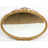 AN OVAL GILT WALL MIRROR with ribbon cresting, 89cm wide x 96cm high overall together with a cream