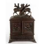 A 19TH CENTURY GERMAN BLACK FOREST TABLE TOP CABINET with carved deer above twin doors with carved