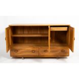 AN ERCOL LIGHT ELM SIDEBOARD with three panelled doors above two drawers, on rollable casters, 130cm