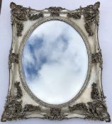 A CONTEMPORARY SILVER PAINTED 18TH CENTURY STYLE WALL MIRROR with bevelled oval mirror plate, 83cm