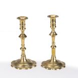 Near pair of brass candlesticks (slight differences) early 18th Century, each on a petal base,