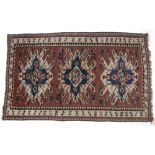 Star Kazak style red ground rug with three central medallions and panel border, 223cm x 139cm